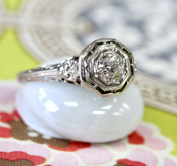 Art Deco diamond engagement ring with calibre emeralds.